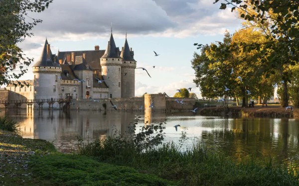 Château de Sully-sur-Loire, a man-made castle reflected in calm waters, surrounded by trees under a partly cloudy sky in a 4K Ultra HD PC desktop wallpaper.