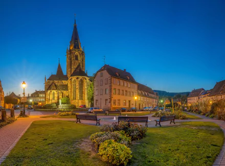 HD PC desktop wallpaper of a man-made village featuring a church with a tall steeple, surrounded by historic buildings and a well-lit town square at dusk.