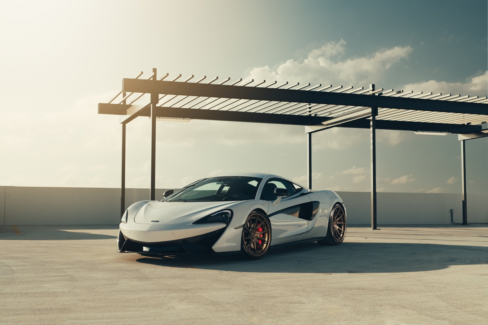 Silver McLaren 570S supercar (car/vehicle) parked under a modern canopy on a rooftop, high-definition PC desktop wallpaper background.