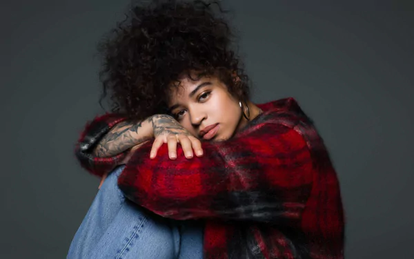 HD desktop wallpaper featuring a thoughtful person wrapped in a red plaid blanket, with a grey background.