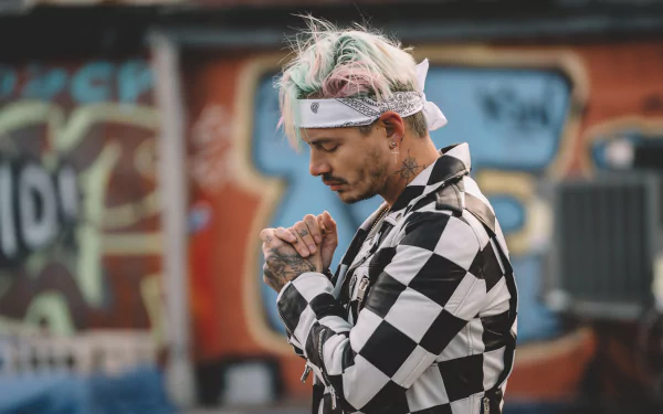 HD desktop wallpaper featuring J Balvin with a graffiti backdrop, dressed in a checkered outfit with a thoughtful expression.