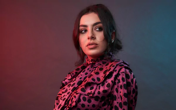 5K desktop wallpaper: close-up of a black-haired woman with brown eyes in a pink polka-dot blouse, red-blue studio lighting, evoking a pop singer/music aesthetic.