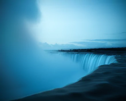 A serene 4K Ultra HD desktop wallpaper capturing the misty, powerful flow of Niagara Falls at dusk, showcasing the beauty of nature and cascading water.