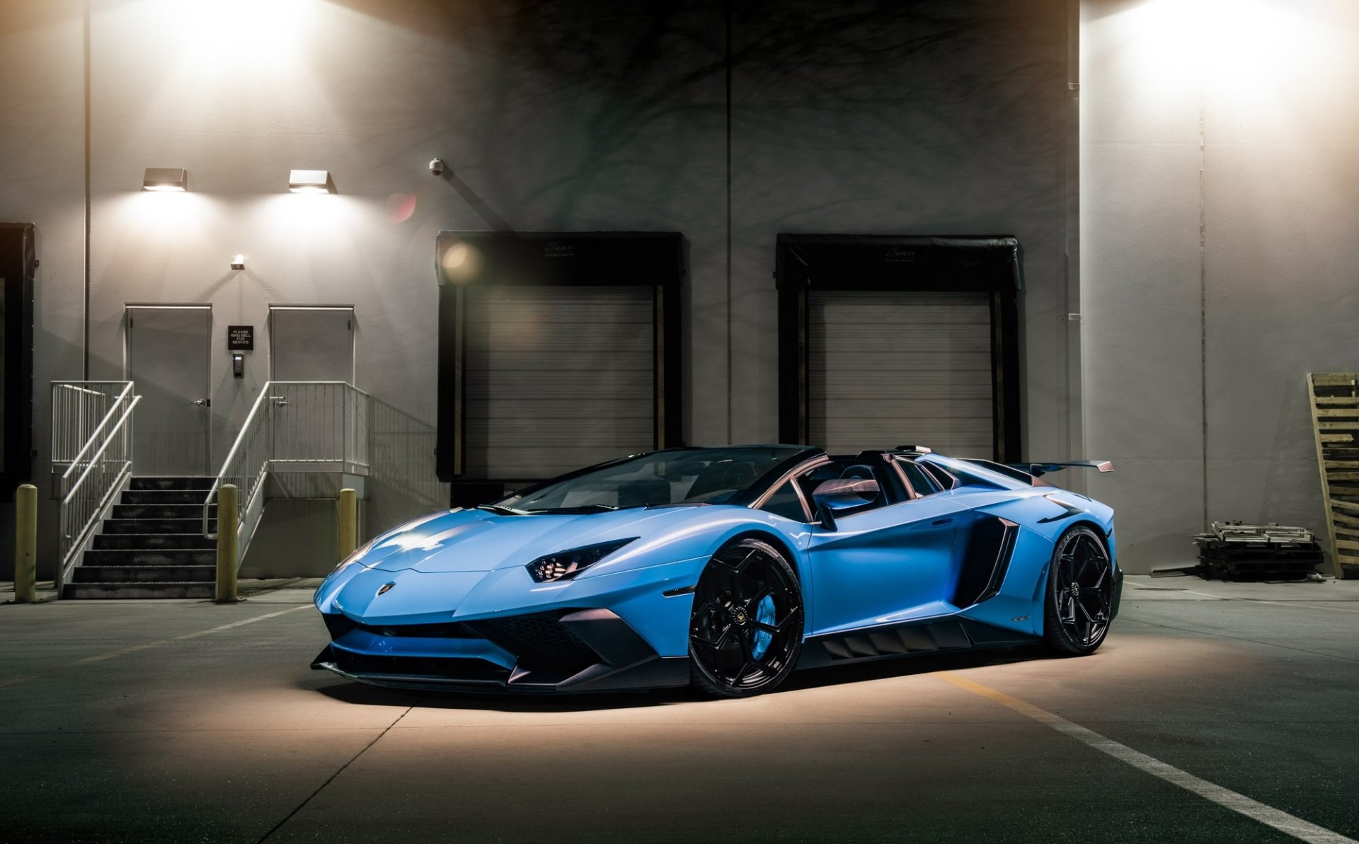 Blue Lamborghini Aventador SV supercar showcased in a dimly lit industrial setting, captured as an HD PC desktop wallpaper and background.