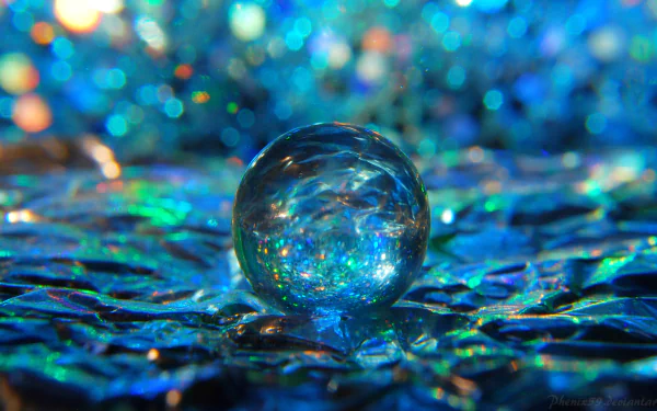 A 4K Ultra HD abstract desktop wallpaper featuring a reflective glass ball resting on a vibrant, textured surface with shimmering blue and green hues.