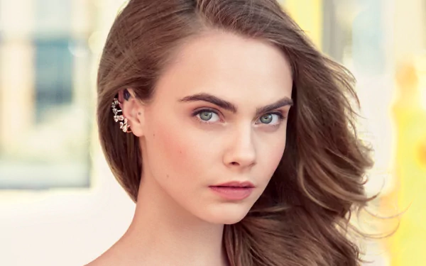 HD PC desktop wallpaper: close-up portrait of a celebrity (identity unspecified) with blue-green eyes, flowing brown hair and decorative ear cuffs against a soft, blurred background.