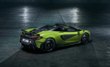 Green McLaren 600LT supercar roadster in a dim industrial setting, showcased as a 2K Quad HD PC desktop wallpaper/background.