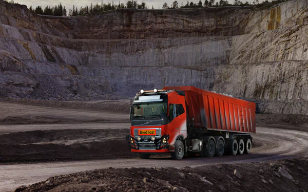 4K Ultra HD image of a red Volvo truck with a large trailer in a rugged quarry setting, designed as a PC desktop wallpaper and background.