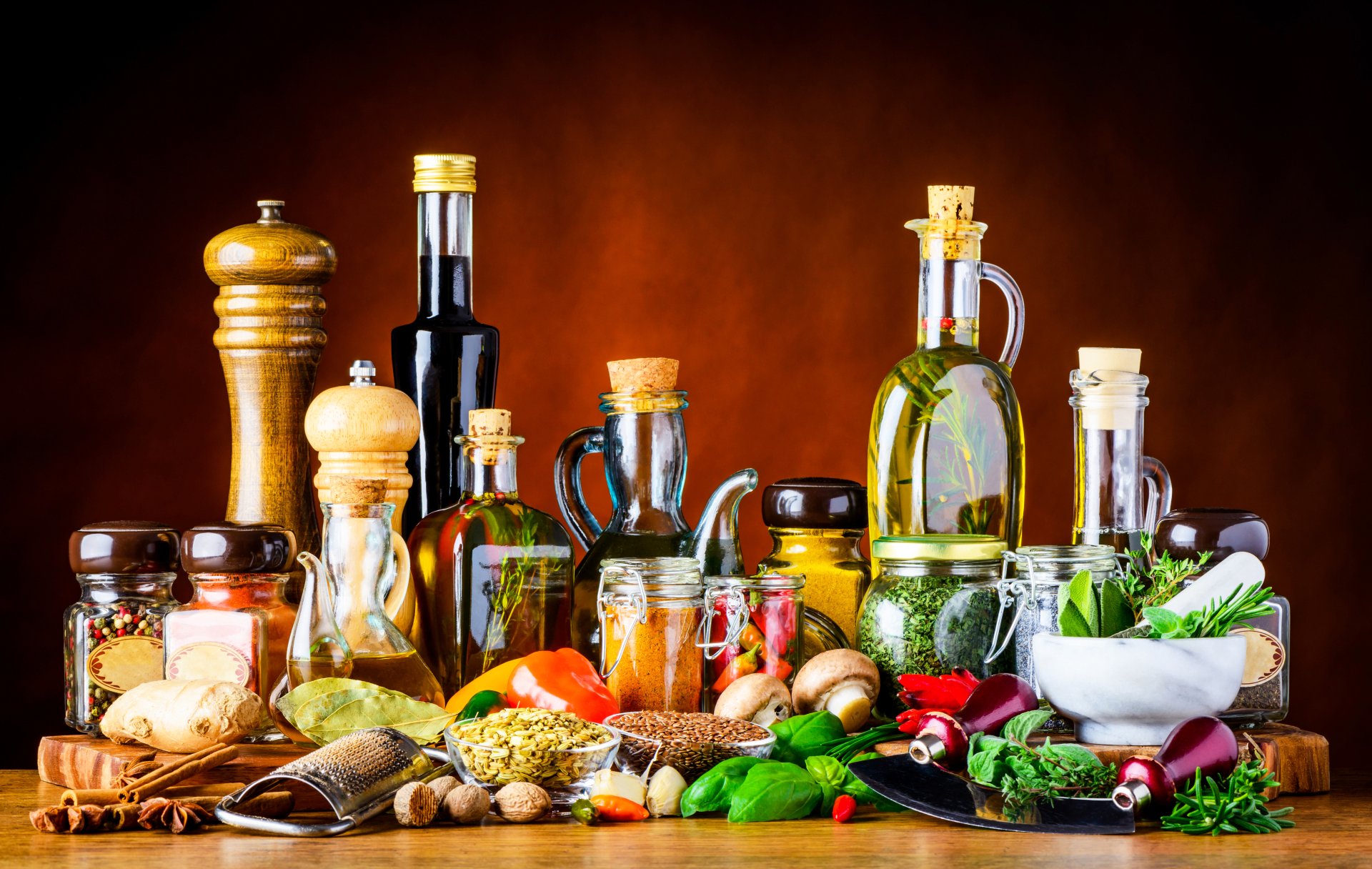 Still life of bottles of oil, jars, herbs, spices and fresh produce on a wooden table — 5K Ultra HD PC desktop wallpaper/background.