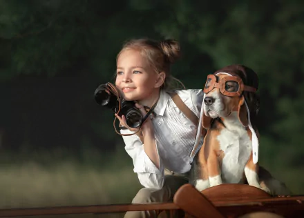 A little girl and her beagle dog with aviator goggles pose outdoors, the girl holding binoculars, captured with a shallow depth of field in this HD desktop wallpaper.
