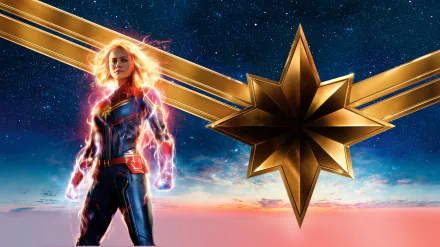 HD desktop wallpaper featuring Brie Larson as Captain Marvel, with a blonde hairstyle, standing against a starry sky background, and the iconic golden star emblem from the Avengers movie series.