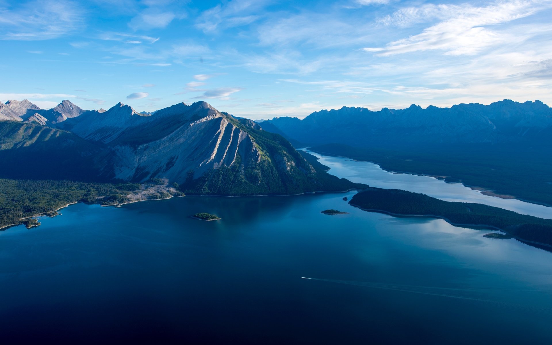 4K Ultra HD desktop wallpaper capturing a serene lake surrounded by towering mountains under a partly cloudy sky.