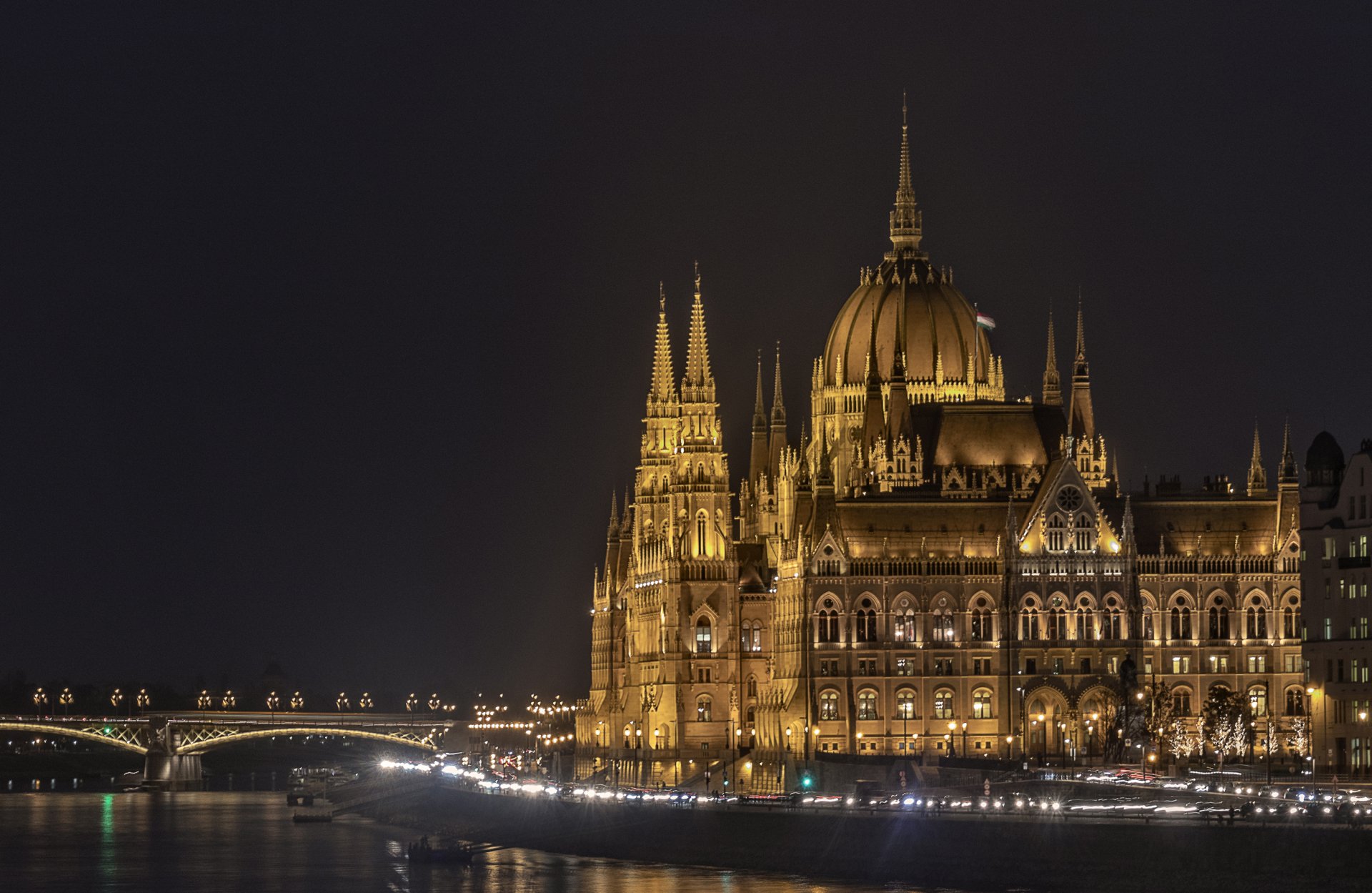 Night view of the illuminated Hungarian Parliament Building in Budapest, Hungary, showcasing its intricate architecture along the river, captured in HD quality.