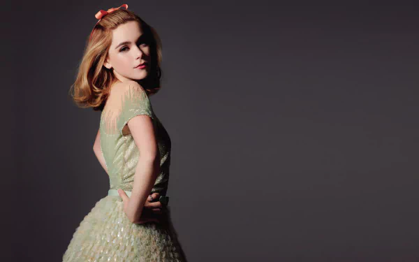 Redheaded woman in a pale green dress poses against a dark backdrop, styled as an elegant HD desktop wallpaper.