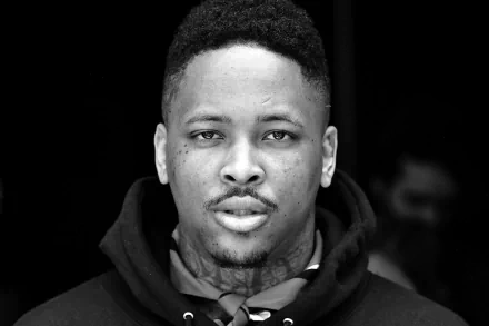 Black and white HD desktop wallpaper featuring a man with tattoos looking intently at the camera, tagged with YG.