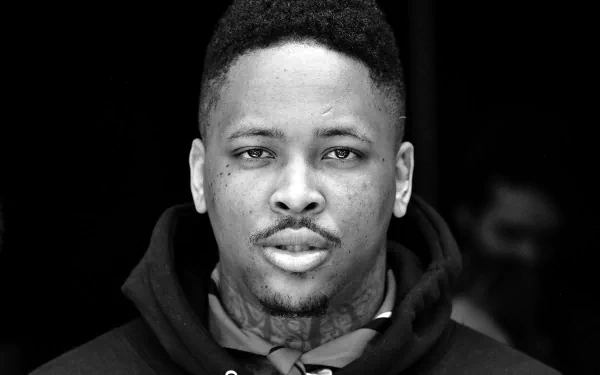 Black and white HD desktop wallpaper featuring a man with tattoos looking intently at the camera, tagged with YG.