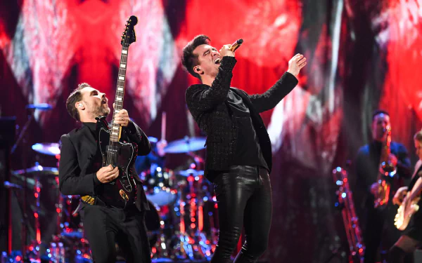 HD desktop wallpaper of Panic! at the Disco band members performing live on stage with vibrant red background.